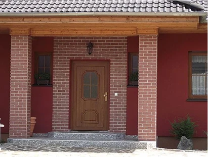 Klassische Haustür in Holzoptik in einem Klinkerportal eines Einfamilienhauses